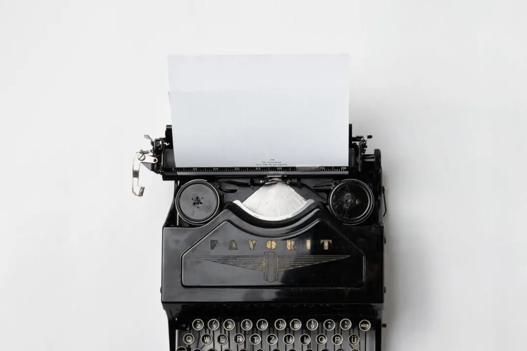 Black typewriter with a blank sheet of paper, on a light background