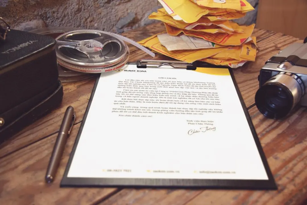 Documento cartaceo su una scrivania di legno, accanto a una macchina fotografica