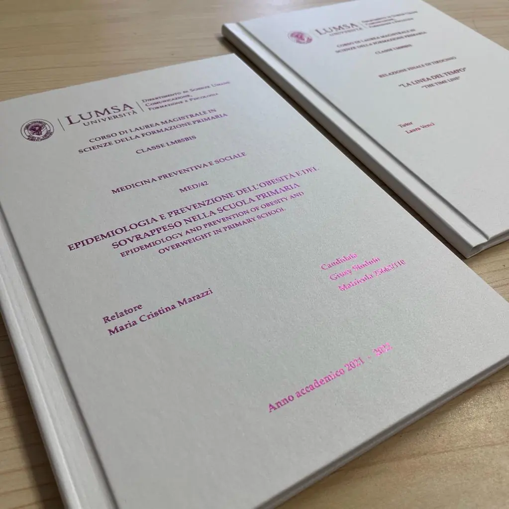 Due tesi di laurea con copertina rigida bianca e stampa foil fucsia, rilegate da GUUG per la LUMSA di Roma