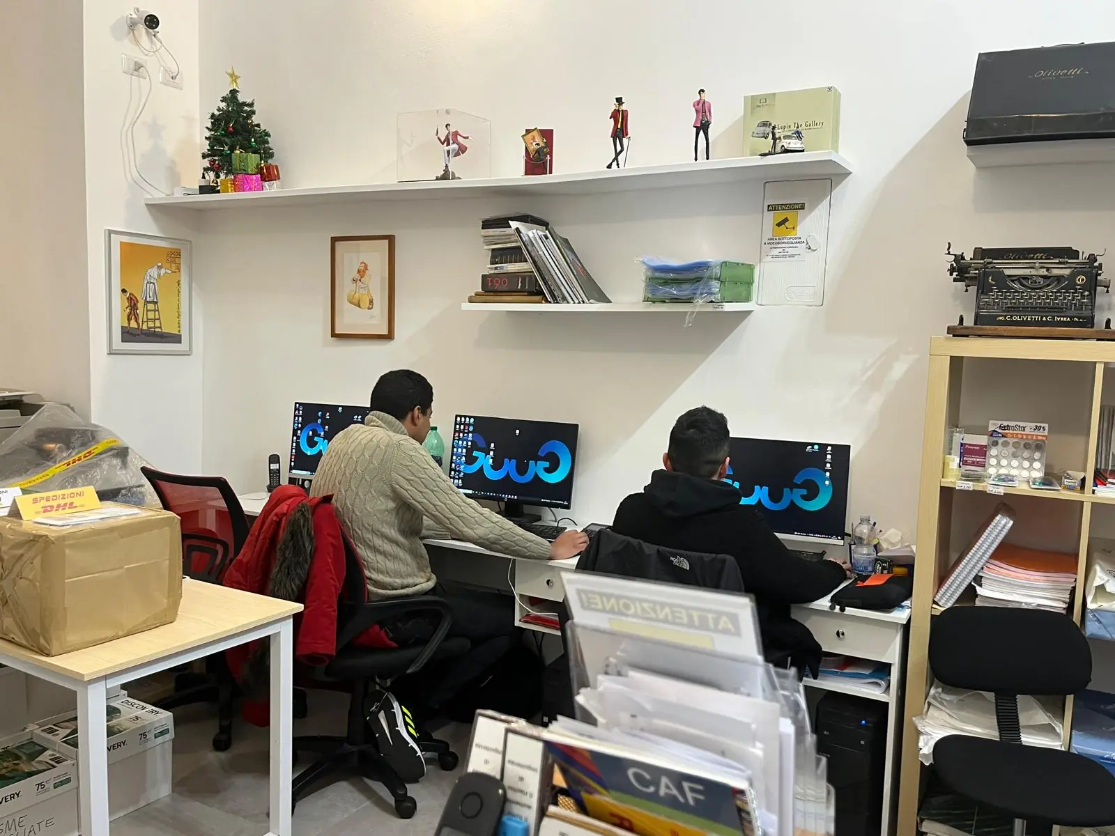 Il banco della copisteria GUUG a Roma Prati: postazioni di lavoro reali con stampanti e monitor, dove si preparano i file dei clienti